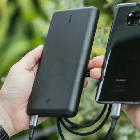 A person holds a power bank whilst charging a mobile phone in the other hand. Photo by SCREEN POST on Pexels.