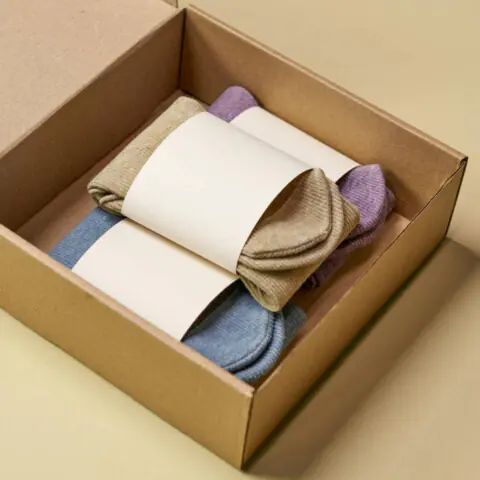 A pile of brand-new wool socks packaged in a cardboard box. Photo by Ron Lach on Pexels.