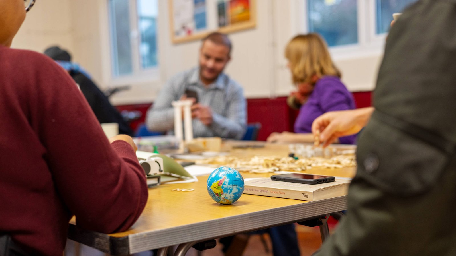 Drop-in centre visitors and volunteers seated around a table participating in a creative workshop.